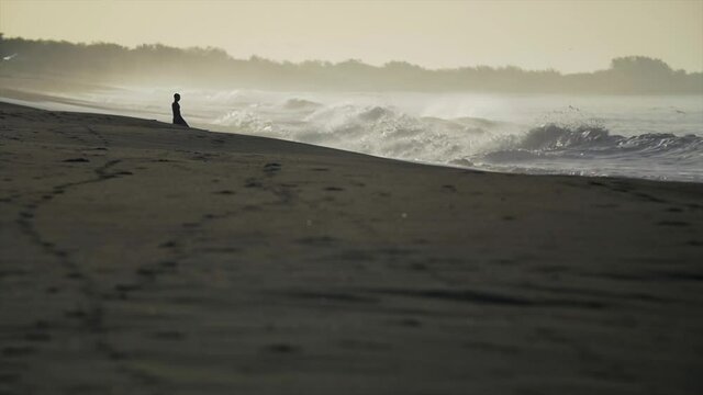 Surfer meditating on beach before starting session, respect for ocean concept