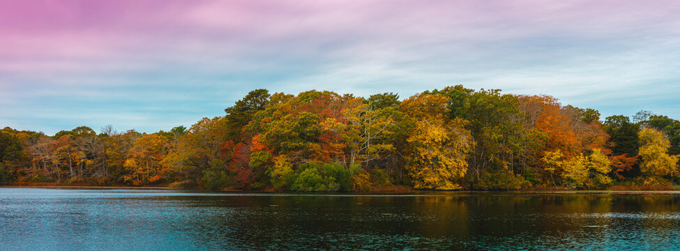 Panoramic autumn lake landscape with colorful foliages and reflections on the water surface