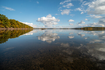 Lake level on an autumn afternoon. Reflecting cloudy sky.