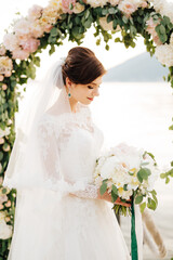 beautiful bride with a veil and bridal bouquet near the wedding arch