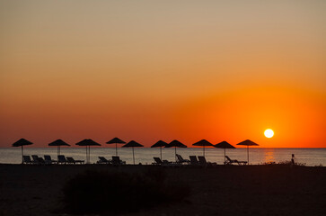 Beach umbrellas on sea at sunrise