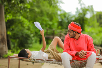 young indian farmer with his child playing with handmade paper airplane