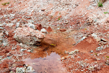High bank of red clay and muddy water of the Volga river bay on a cloudy day.