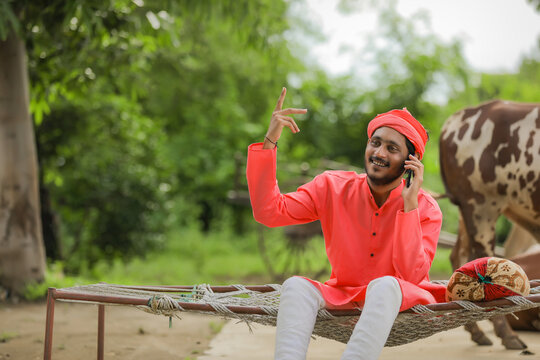 Young Indian farmer talking on mobile phone and showing happy expression