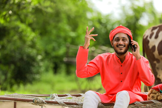 Young Indian farmer talking on mobile phone and showing happy expression