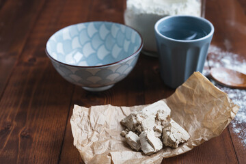 Bits of yeast on paper on a wooden base for making sourdough. Bakery concept.