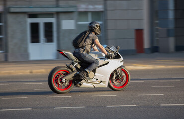 Obraz na płótnie Canvas Motorcyclist in a Helmet Rides a Motorcycle along a city street.