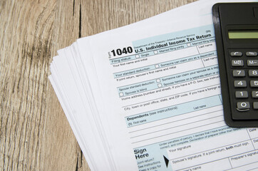 tax forms 1040 with a calculator on a wooden table. Financial document.