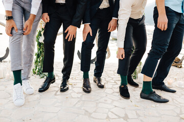 Fototapeta na wymiar the groom and the best men show that they are wearing the same green socks