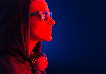 Portrait of a woman dressed in hooded, sunglasses and headphones.