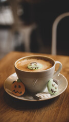 Cup of latte coffee wrapped in hands with Halloween marshmallows	