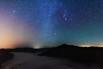 A beautiful starry night in the mountains on top with beautiful scenery and fog.