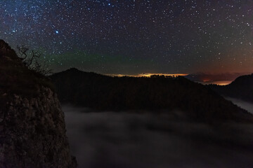 A beautiful starry night in the mountains on top with beautiful scenery and fog.