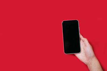 Fototapeta na wymiar Hand holding a phone on the red background mock up
