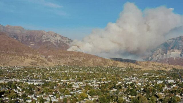 Aerial shot of DC-10 dumping fire retardant on wildfire on mountain above city from a safe distance, Orem Utah