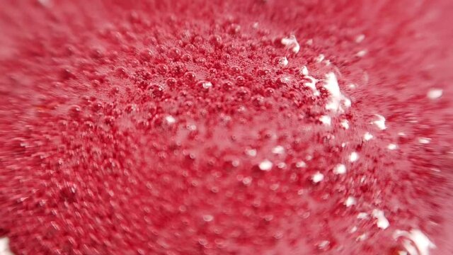 Raspberry jam in the process of boiling. Raspberry syrup. Pink background with bubbling bubbles and raspberries. Procedure for harvesting berries for the winter. Cooking raspberries with sugar. Backgr