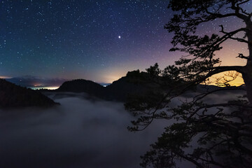 A beautiful starry night in the mountains on top with beautiful scenery and fog.