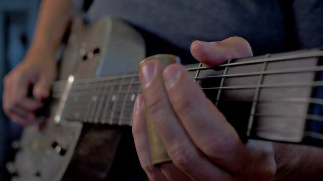 Man Playing Old Metallic Resonator Guitar with Slide Close Up Neck