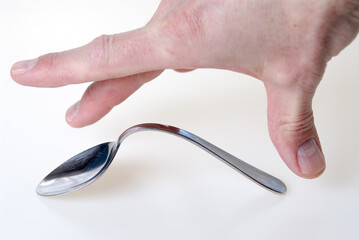 Hand of man bending a spoon by power of telekinesis