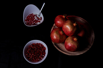 Pomegranates in table and seeds in bowl with yogurt
