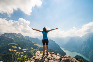 Girl standing on the top of a cliff watching a beautiful mountain scenery in the bavarian Alps