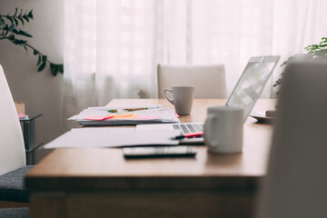Busy desk for two workers in home office space. Laptop and paperwork.