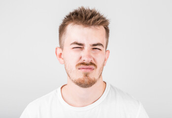 Obraz premium Unsatisfied sleepy guy with messy hair and gloomy smile, standing over gray background.