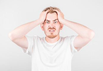Fototapeta premium Embarrassed fashionable young man being afraid of difficulties, stands against white background