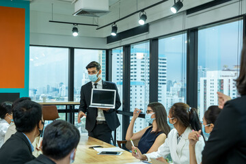 Group of business people with face mask protect from Coronavirus or COVID-19 discussing project plan at in boardroom,support together to overcome pandemic of Coronavirus to reopen business.