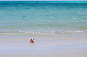 Fototapeta na wymiar A soccer ball alone on the sandy beach in front of the turquoise ocean in the Caribbeans