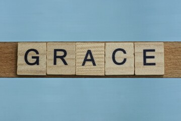  gray word grace in small square wooden letters with black font on a blue background