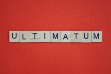 text the word ultimatum from gray wooden small letters with black font on an red table