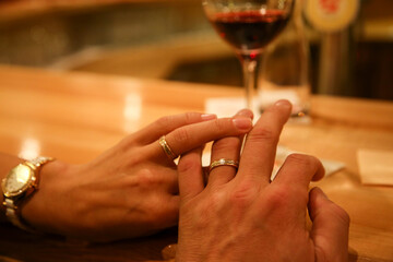 Hands of man and woman showing their wedding rings in cozy atmosphere in bar