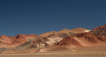 Fototapeta na wymiar The Andes mountain range. Panorama view of the beautiful brown mountains high in the cordillera, under a deep blue sky.