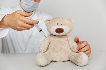 Pediatrician makes an injection for teddy bear. Child healtcare and treatment concept.
