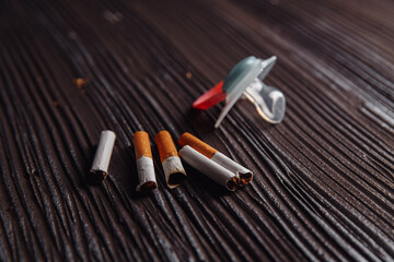 Stop smoking concept. Cigarettes and baby pacifier on a wooden table.