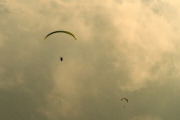 Silhouette of paragliders in a wonderful sunset light flying in clouds. Extreme sport