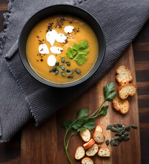 Pumpkin soup with cream, pumpkin seeds and parsley and side of croutons