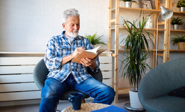 Happy senior man reading book at home