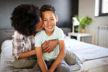 Happy mother playing, having fun, hugging with her son at home