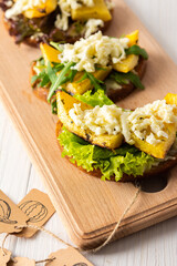 Toasted sandwiches with brie cheese, baked pumpkin and salad, arugula and mozzarella, delicious vegetable snacks on a wooden board