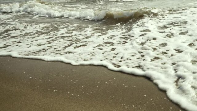 Sea waves rolling over the fine sand beach - close up