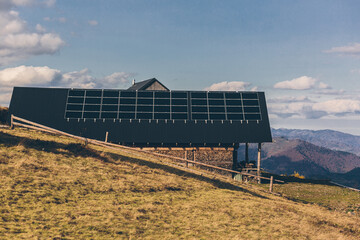 photo of a house in the mountains, on the roof of a solar panel, sunset