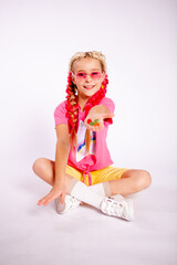 a cute girl in bright colorful clothes and with colored braids shows gelatinous gummies
