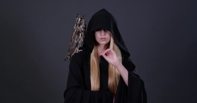 Beautiful witch with her owl familiar on grey background