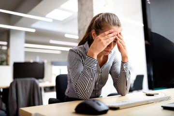 Overworked and frustrated young woman in front of computer in office