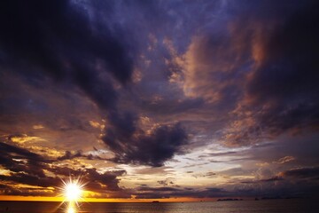 Dramatic threatening  sky clouds sunset after tropical rain thunder storm with bright sun star over...