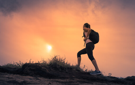 silhouette of a person hiking up mountain at sunrise