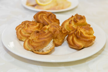 Obraz na płótnie Canvas Eclairs with cream on a platter. Sweet tender dessert pastry.