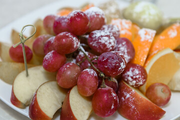 Vitamin Fruits on a platter. Grapes, apples and oranges for food.